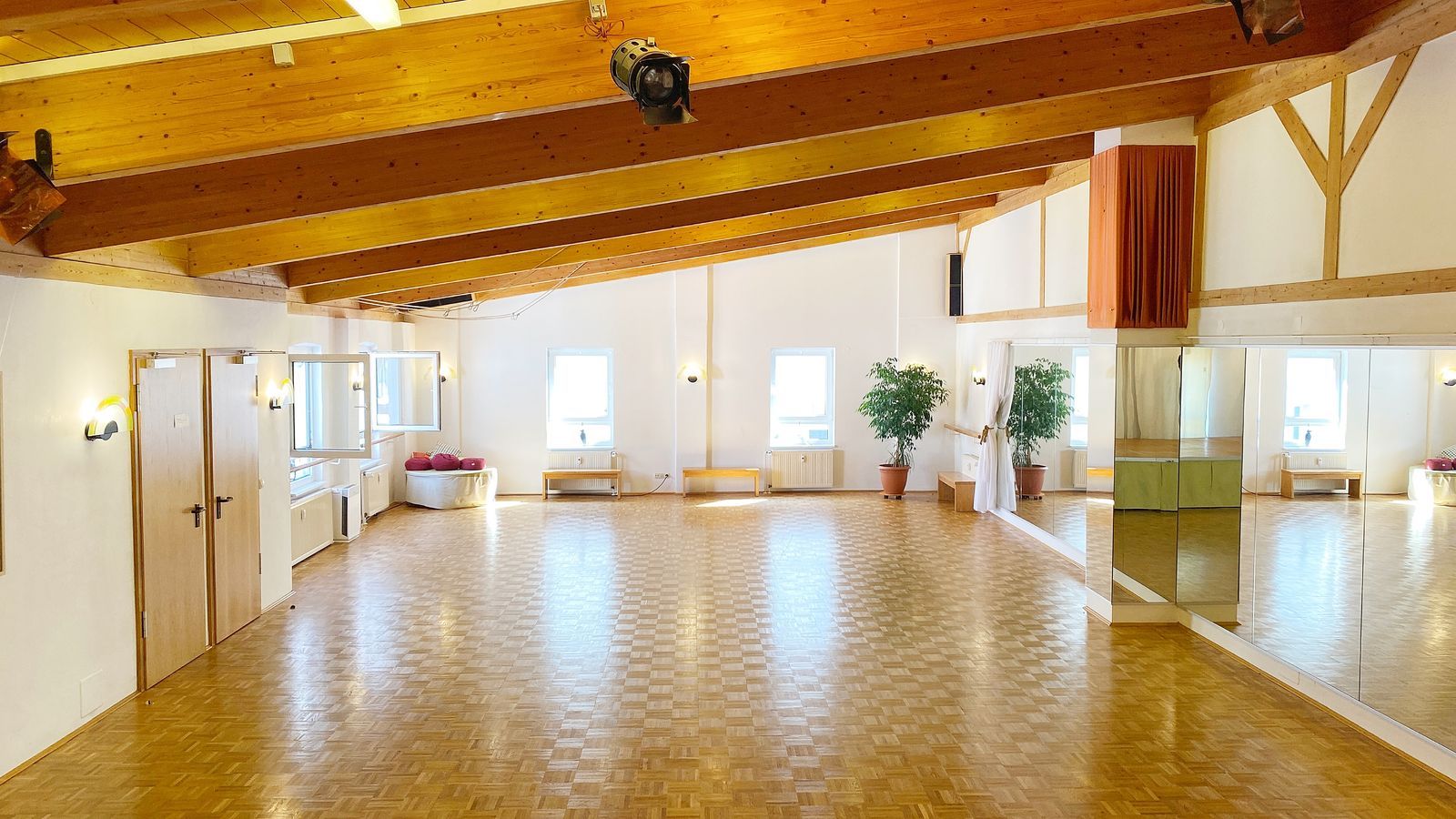 Der gesamte 140 m² große Tanzsaal in Nürnberg: Parkettboden, Spiegelwand, Fensterfront und offene Holzbalkendecke